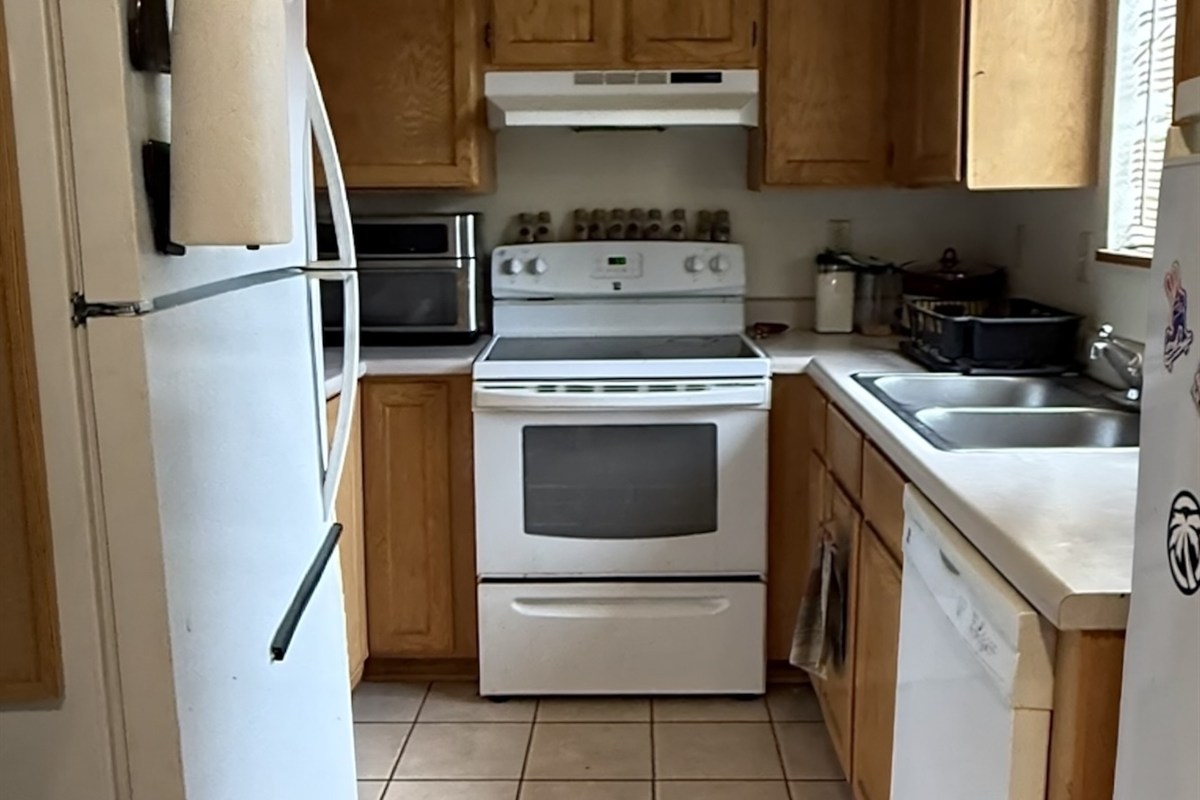 A Venture on Lockett kitchen before renovation: original oak cabinets, dated white appliances and beige tile floor